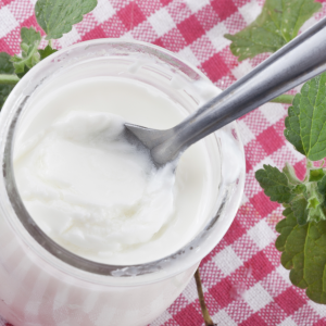 Glas yoghurt op een geblokt tafellaken met muntblaadjes