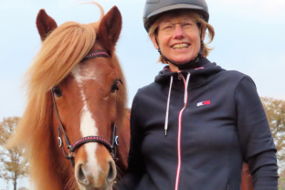 Loethe Olthuis met cap en bruin paard aan rechterhand