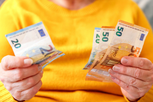 Vrouw houdt eurobriefjes van 20 en 50 in haar handen