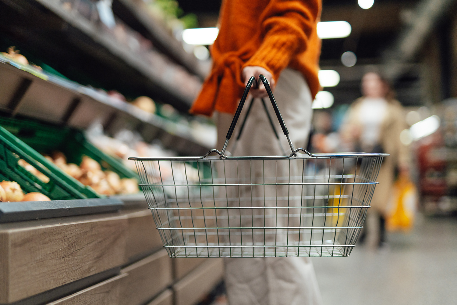 In de supermarkt houdt iemand een leeg boodschappenmandje vast